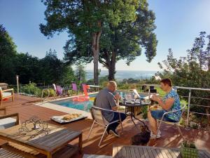 um homem e uma mulher sentados numa mesa junto a uma piscina em Le Belvedere des Remparts em Langres