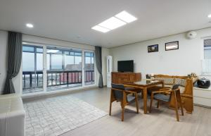 a living room with a table and chairs and a television at Herkules Namhae German Village in Namhae