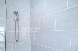 bagno con doccia e piastrelle bianche di The Hide Away Modern Rooms a Norwood