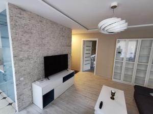 sala de estar con TV de pantalla plana en una pared de ladrillo en ALDO comfort en Ludza