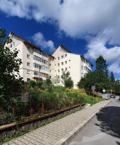 Deux bâtiments blancs avec des fleurs devant une rue dans l'établissement Andi Apartament, à Predeal