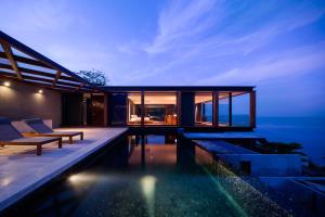 a modern house with a swimming pool at night at The Naka Phuket, a Member of Design Hotels - SHA Extra Plus in Kamala Beach
