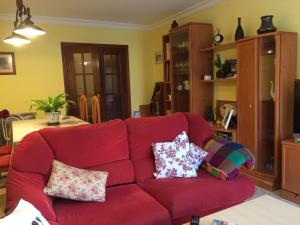 czerwoną kanapę w salonie z poduszkami w obiekcie Como en casa w Maladze