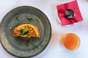 a table with a plate of food and a cup of orange juice at La Tambra - Residence - Central with Restaurant in Santa Cristina Gherdëina