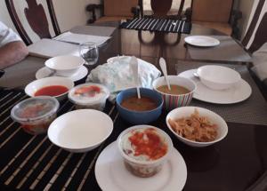 einen Tisch mit Schalen und Teller mit Lebensmitteln darauf in der Unterkunft Sarai Silk Route in Islamabad