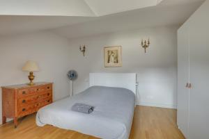 a white bedroom with a bed and a dresser at Le Richelieu in Versailles