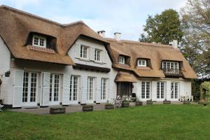 a large white house with a thatched roof at Villa Monceau Louvain la neuve in Louvain-la-Neuve