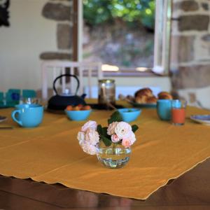 uma mesa com uma taça de vidro com flores em Le cottage du séquoia em Chamberet