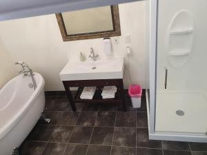 Inglewood的住宿－Fernlodge Inglewood，浴室配有盥洗盆、浴缸和盥洗盆