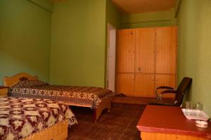 1 dormitorio con 2 camas, armario y mesa en Capital Lodge, en Gilgit