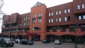 a large brick building with cars parked in a parking lot at Sieć Hoteli Fort Warszawa in Warsaw