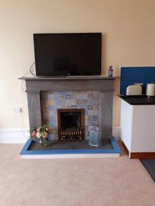 a living room with a fireplace with a tv above it at Commodore Guesthouse, Self-Catering Suites in Rothesay