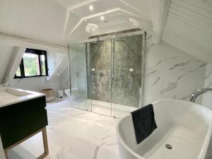 a bathroom with a tub and a glass shower at L'hermine de Sologne in Courmemin