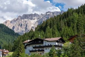 een groot wit gebouw voor een berg bij Hotel Monte44 in Selva di Val Gardena