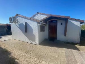 a small white house with a brown door at Vakantiehuisje Wenduine in De Haan