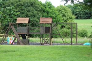 a playground in a park with two wooden swings at Cherry Trees in Stowmarket