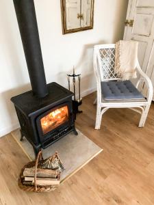 einen Kamin im Wohnzimmer mit einem Stuhl und einem Sofa in der Unterkunft Charzykówka Domek na Kaszubach in Charzykowy