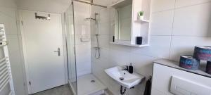 ein weißes Bad mit einer Dusche und einem Waschbecken in der Unterkunft Fewo-Alter PlusSize in Wilhelmshaven