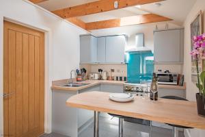 cocina con armarios blancos y encimera de madera en The Roost by Bloom Stays, en Wingham
