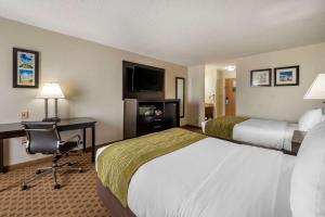 Habitación de hotel con 2 camas, escritorio y TV. en Comfort Inn East, en Indianápolis