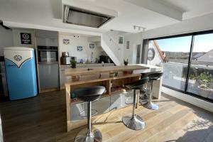 una cucina con bancone e sgabelli in una stanza di DUPLEX AVEC JACUZZI vue imprenable sur la baie de Wissant a Wissant