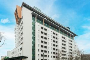 a white building with green windows at Etna Apartments Kołobrzeg by Renters in Kołobrzeg