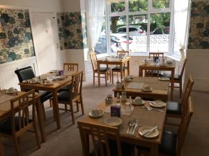 a restaurant with wooden tables and chairs and a window at The Kenmore Guest House in Llandudno
