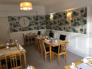 un restaurante con mesas y sillas de madera y un reloj en la pared en The Kenmore Guest House en Llandudno