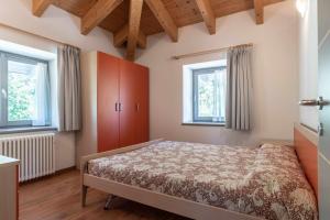 Un dormitorio con una cama y dos ventanas. en Appartamento alla Preda Grauno Ospitar, en Grauno
