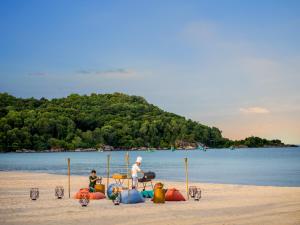 Ein Mann und ein Kind sitzen am Strand in der Unterkunft New World Phu Quoc Resort in Phu Quoc