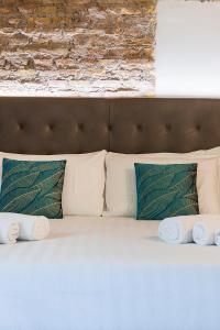 a white bed with pillows and a brick wall at Beyond Colosseum in Rome