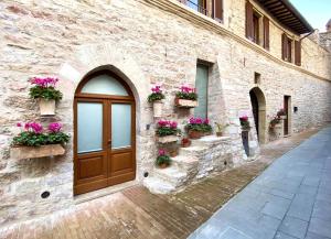 - un bâtiment en pierre avec une porte en bois et des boîtes de fleurs dans l'établissement Camere Capobove Assisi, à Assise