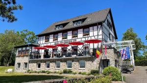 een groot stenen gebouw met rode parasols erop bij Boutique Hotel Restaurant Hollerather Hof in Hellenthal