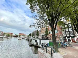 a river with buildings and bikes parked next to a tree at Hotel Oscar in Amsterdam