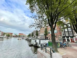 une rivière avec des bâtiments et des vélos garés à côté d'un arbre dans l'établissement Hotel Oscar, à Amsterdam