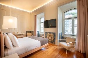a hotel room with a bed, television and a window at Memoria Lisboa FLH Hotels in Lisbon