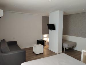 Habitación con cama, sofá y TV. en Hotel Las Terrazas, en Burgos