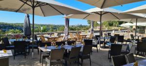 un restaurant avec des tables, des chaises et des parasols dans l'établissement Logis Hotel Bellaroc, à Rocamadour