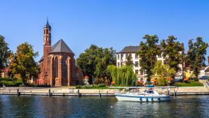 a boat in the water in front of a building at Wunderschöne Ferienwohnung in Brandenburg an der Havel