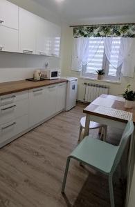 a kitchen with white cabinets and a table with a chair at Apartament Anna Iwonicz Zdrój in Iwonicz-Zdrój