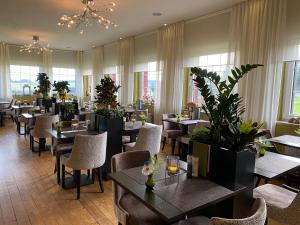 a restaurant with tables and chairs and plants at Boutique Hotel Restaurant Hollerather Hof in Hellenthal