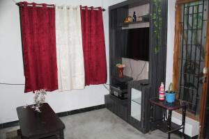 uma sala de estar com cortinas vermelhas e uma mesa em FriendlyStay at Madanandapuram em Chennai