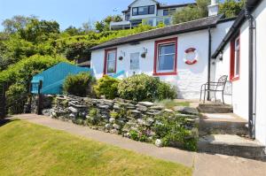 a white house with a stone wall and a yard at Arthur's Seat in Innellan