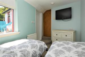 a bedroom with a bed and a tv on the wall at Arthur's Seat in Innellan