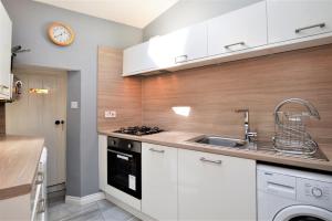 a kitchen with white cabinets and a sink and a clock at Arthur's Seat in Innellan
