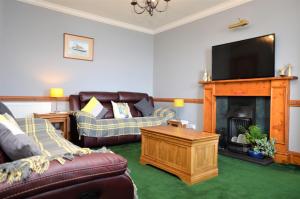 Arthur's Seat في Innellan: غرفة معيشة مع كنب وتلفزيون ومدفأة