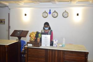 une femme portant un masque dans une pièce avec des horloges dans l'établissement Le Chateau, à Pondichéry