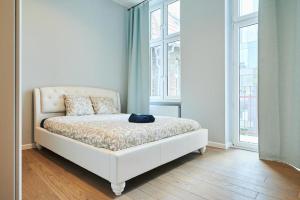 a white bed in a room with windows at Art Deco Apartment in Gdańsk in Gdańsk