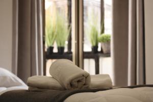 - une pile de serviettes sur un lit avec une fenêtre dans l'établissement ToledoRooms Palacios, à Tolède