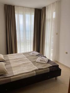 a bed in a bedroom with a large window at Apolon Complex in Sozopol